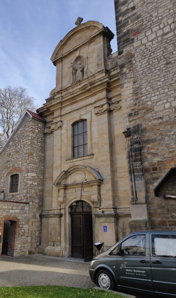 Albatros-Bestattungen® Eingang zur Kirche mit Bestattungswagen im Vordergrund
