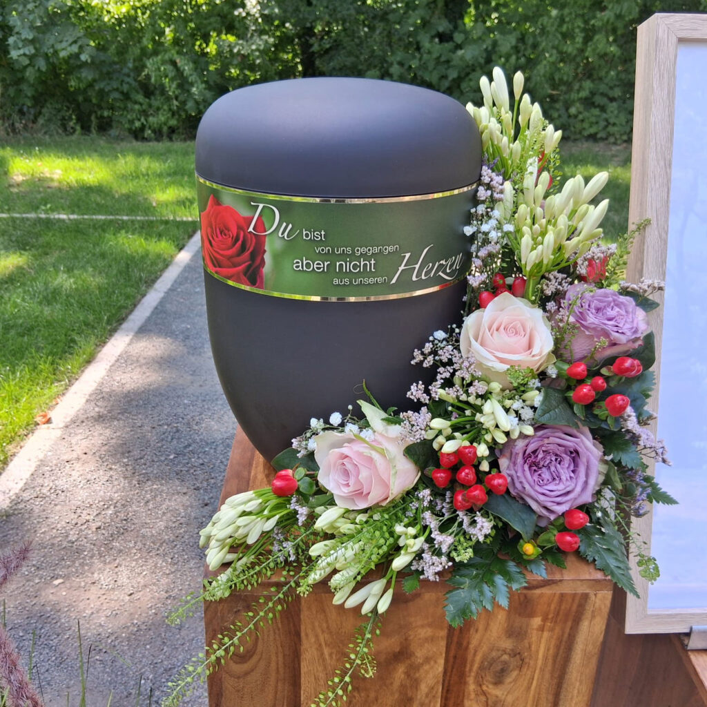 Albatros-Bestattungen® Urne mit Blumengesteck auf dem Friedhof
